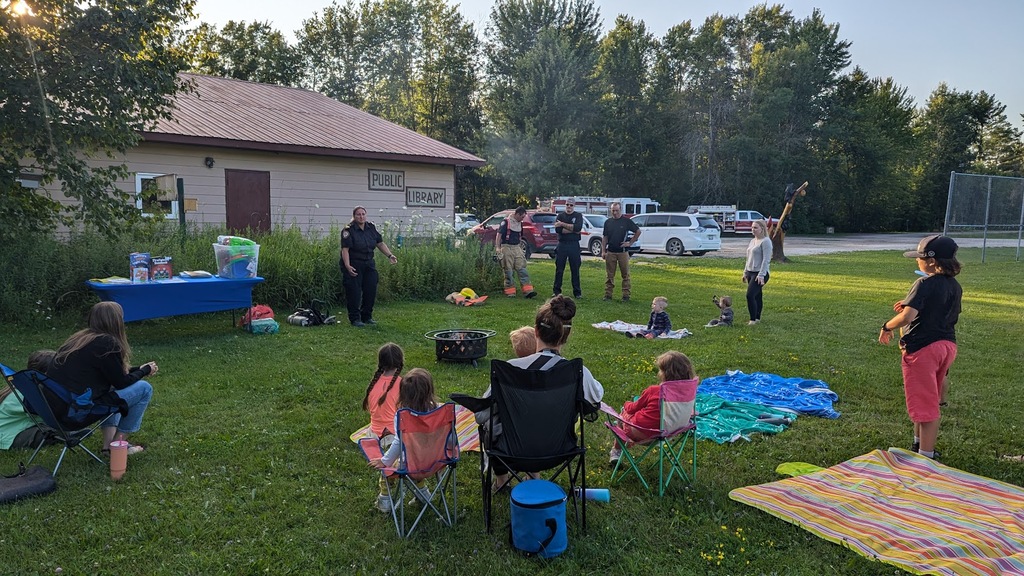 Children and adults relax outdoors on lawn chairs.