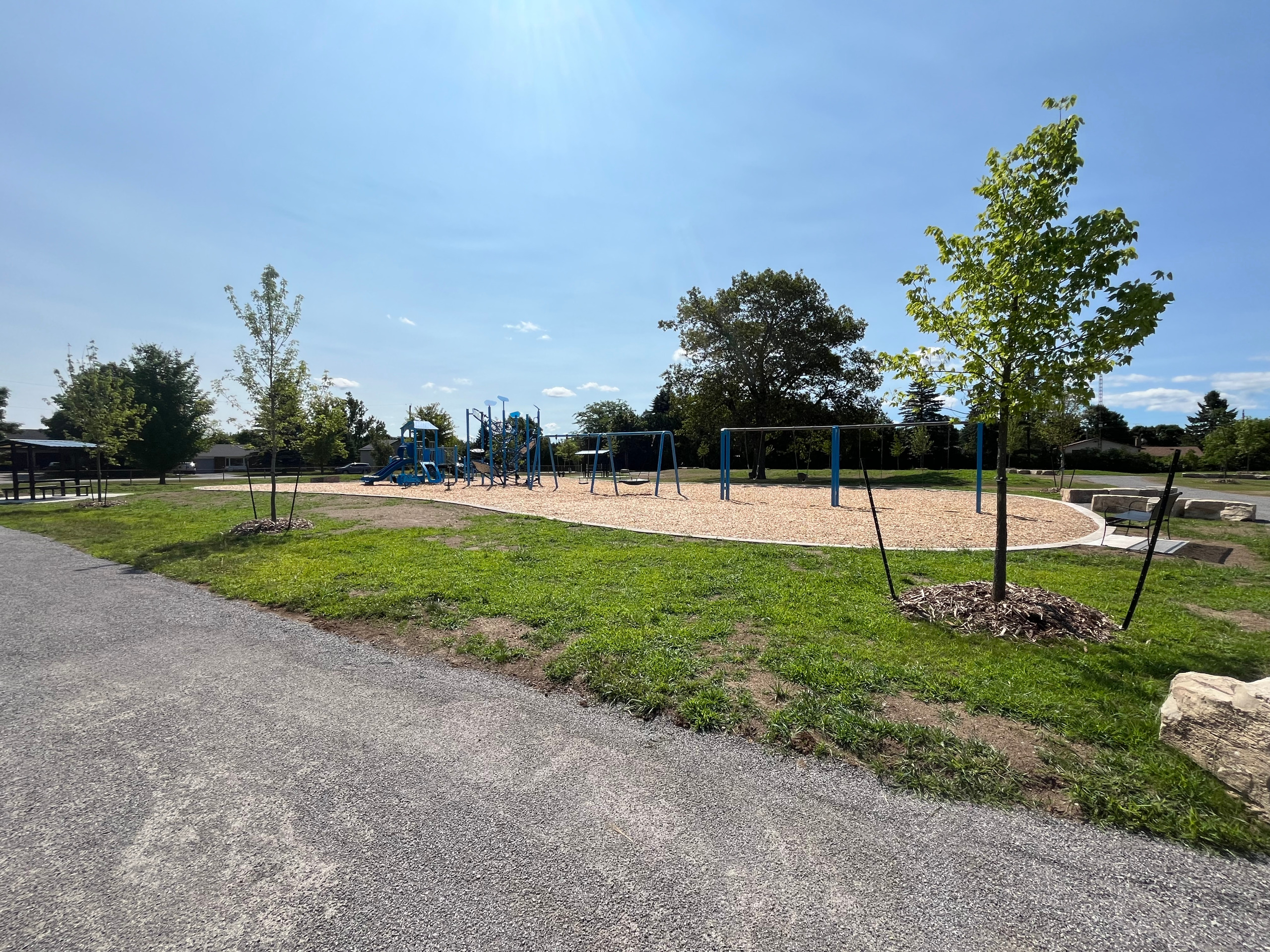 Playground equipment surrounded by grass with a blue sky background.