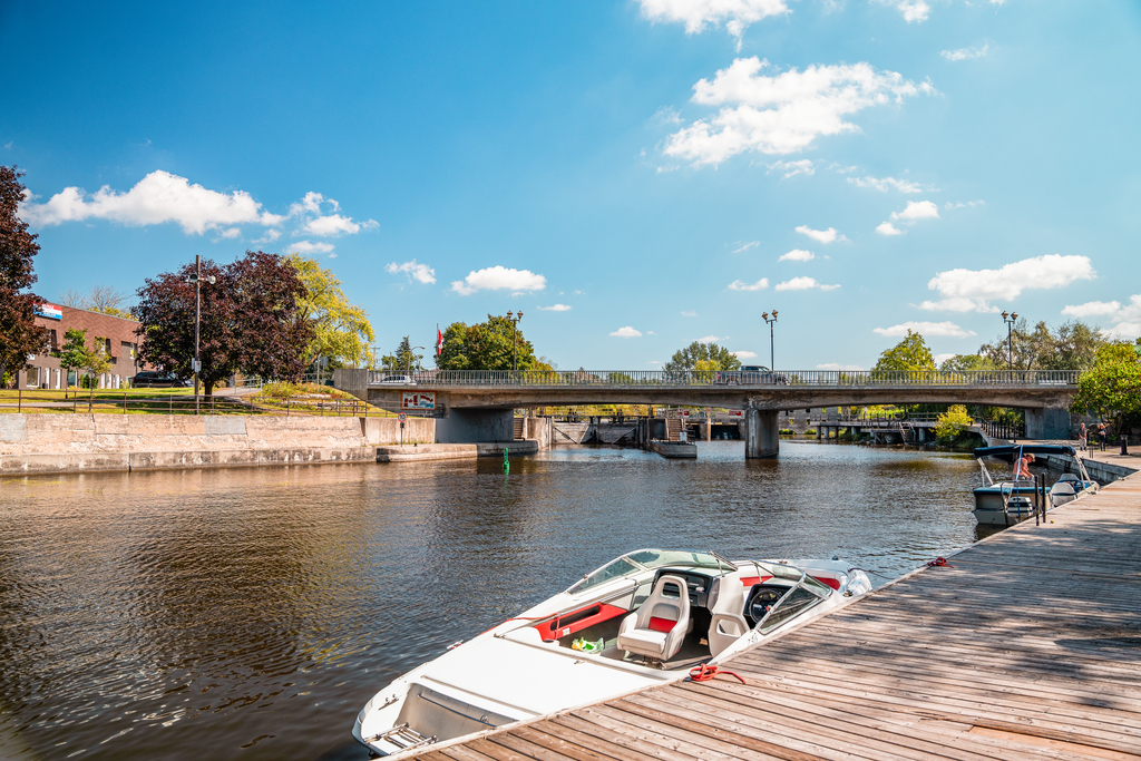 Boat docked alongside a boardwalk. A river is calm in the background.